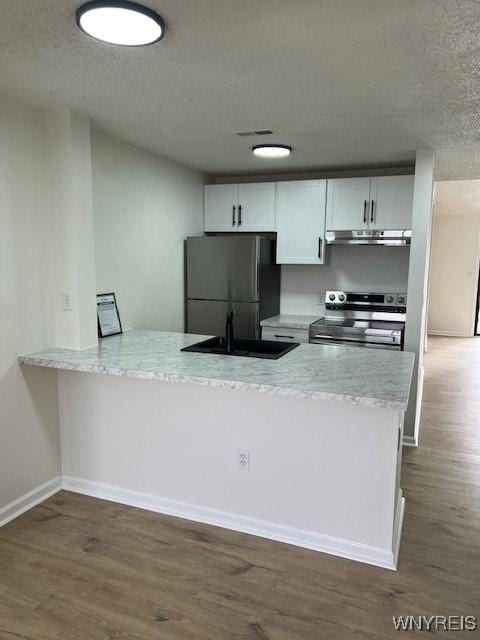 kitchen with dark hardwood / wood-style floors, white cabinets, black fridge, stainless steel range with electric cooktop, and kitchen peninsula