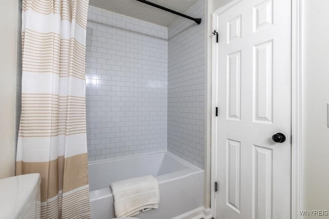 bathroom with shower / bathtub combination with curtain and a textured ceiling