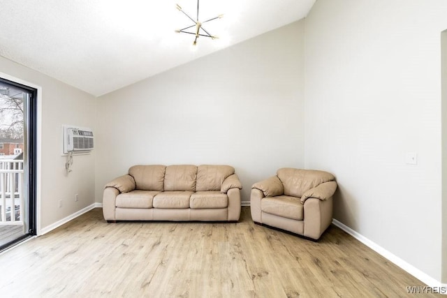 living room with lofted ceiling, a notable chandelier, light hardwood / wood-style flooring, and an AC wall unit