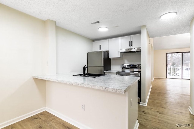 kitchen with stainless steel appliances, kitchen peninsula, sink, and white cabinets