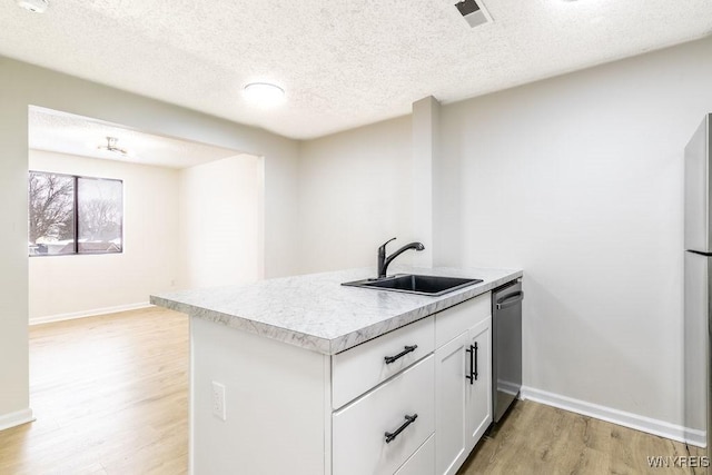 kitchen with sink, light hardwood / wood-style flooring, dishwasher, white cabinetry, and a textured ceiling