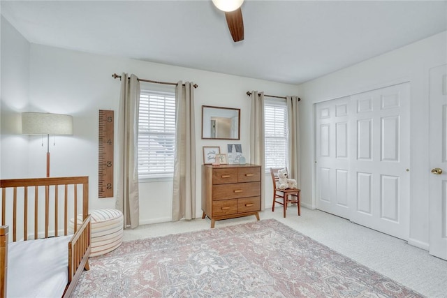 bedroom featuring light colored carpet, ceiling fan, and a closet