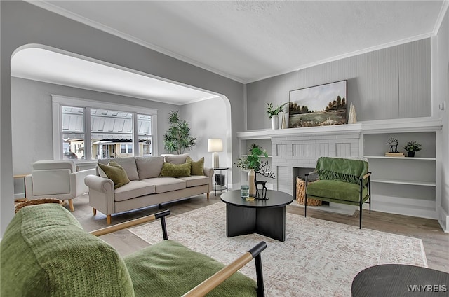 living room with wood-type flooring, a brick fireplace, and crown molding