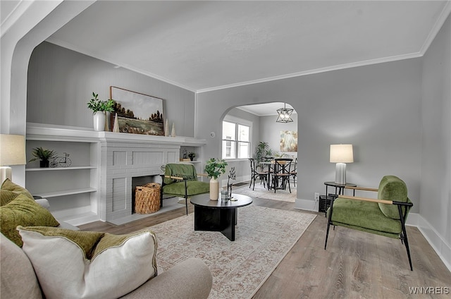 living room featuring a brick fireplace, crown molding, and light wood-type flooring