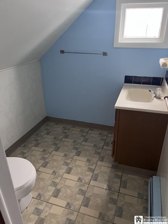 bathroom featuring vanity, lofted ceiling, and toilet