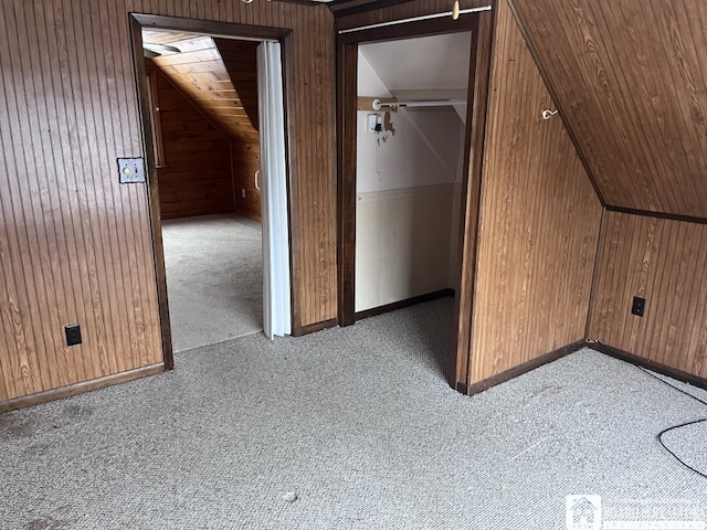 additional living space with light carpet, wooden walls, and vaulted ceiling