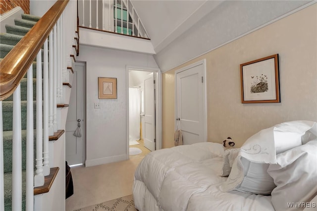 carpeted bedroom featuring high vaulted ceiling and ensuite bathroom