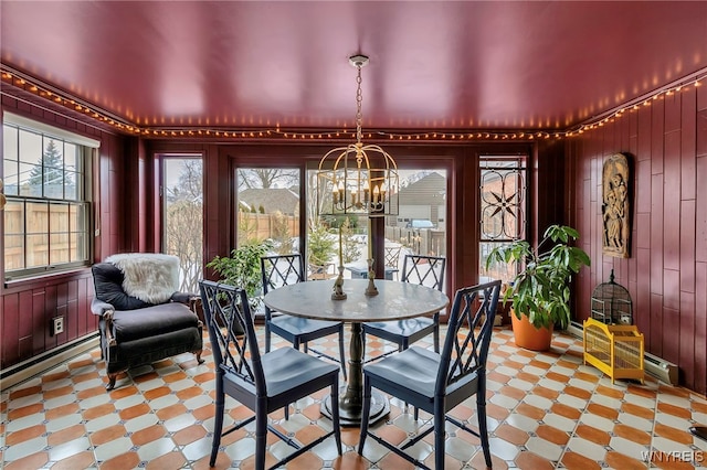 dining area featuring a notable chandelier, a wealth of natural light, and wood walls