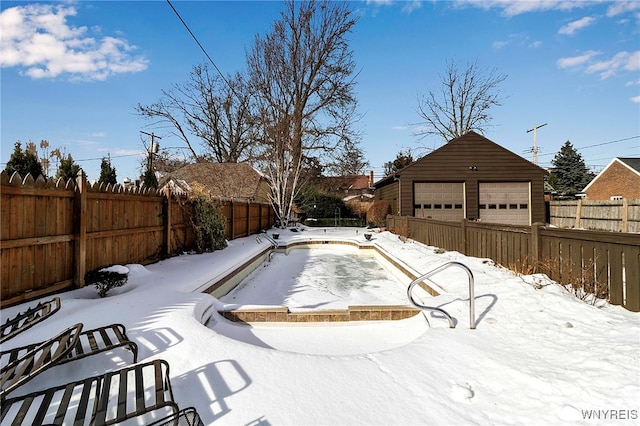 snow covered pool with a garage and an outdoor structure