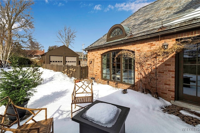 snow covered patio with a garage and an outdoor structure