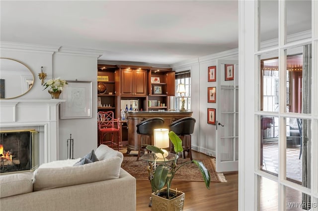 living room with ornamental molding, indoor bar, and wood-type flooring