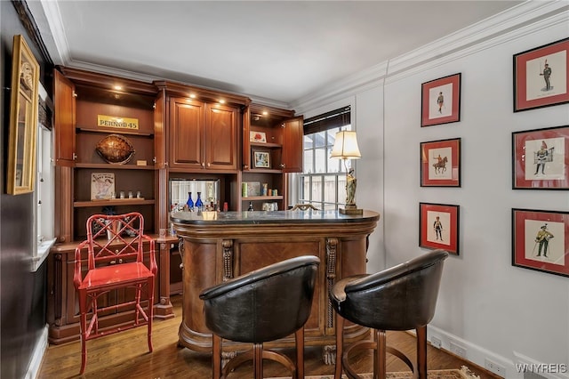 bar featuring dark wood-type flooring, ornamental molding, and hanging light fixtures