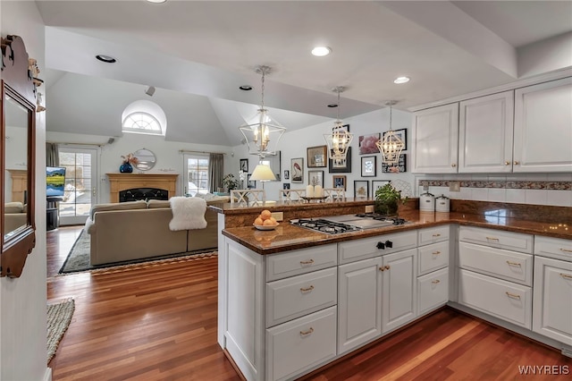 kitchen with white cabinetry, stainless steel gas stovetop, kitchen peninsula, and hanging light fixtures