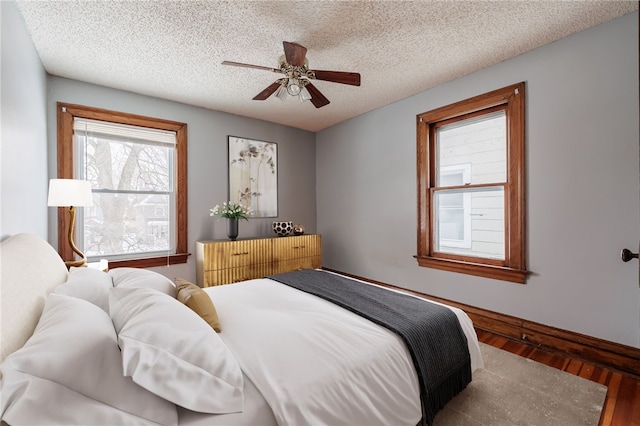 bedroom featuring dark hardwood / wood-style flooring, ceiling fan, and a textured ceiling