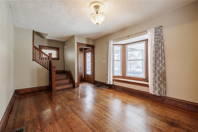 foyer entrance with a healthy amount of sunlight, a textured ceiling, and dark hardwood / wood-style flooring