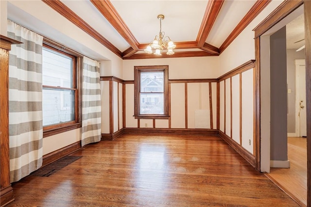 spare room with hardwood / wood-style flooring, crown molding, and a notable chandelier