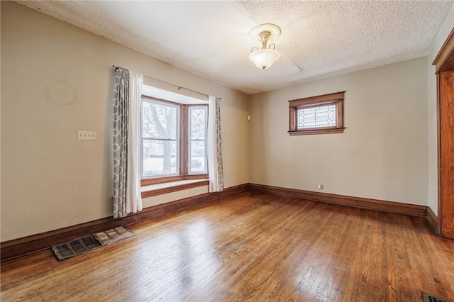 unfurnished room with hardwood / wood-style floors and a textured ceiling