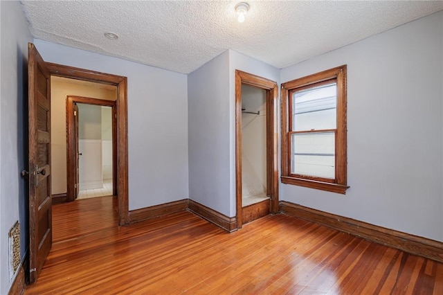 unfurnished bedroom with hardwood / wood-style floors, a closet, and a textured ceiling