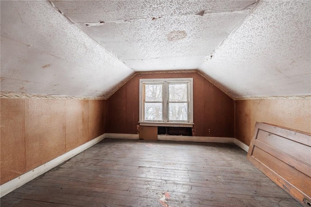 bonus room featuring lofted ceiling, wood-type flooring, and a textured ceiling