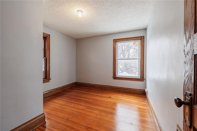 empty room featuring a textured ceiling and light hardwood / wood-style floors