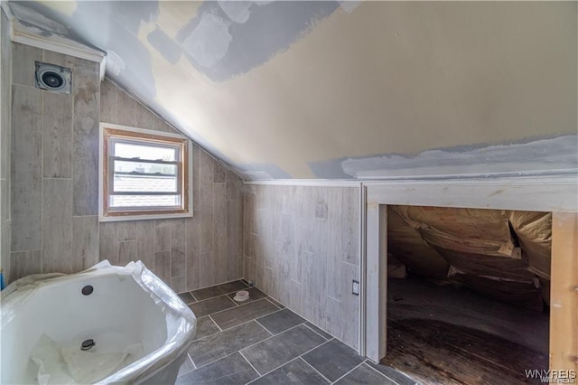 bathroom with tiled bath and vaulted ceiling