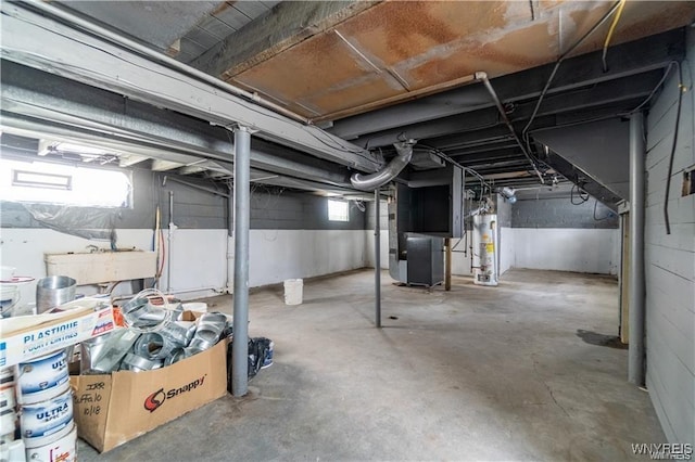 basement featuring heating unit, gas water heater, and a healthy amount of sunlight