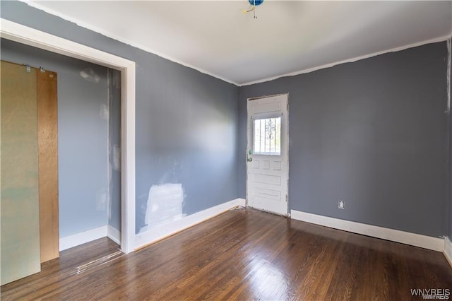 unfurnished room featuring ornamental molding and dark hardwood / wood-style floors