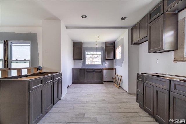 kitchen with pendant lighting, sink, dark brown cabinets, and light hardwood / wood-style floors