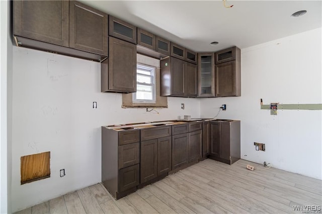 kitchen with dark brown cabinetry, sink, and light hardwood / wood-style floors