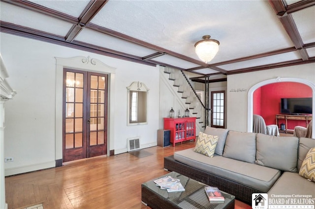 living room featuring hardwood / wood-style flooring, coffered ceiling, beam ceiling, and french doors