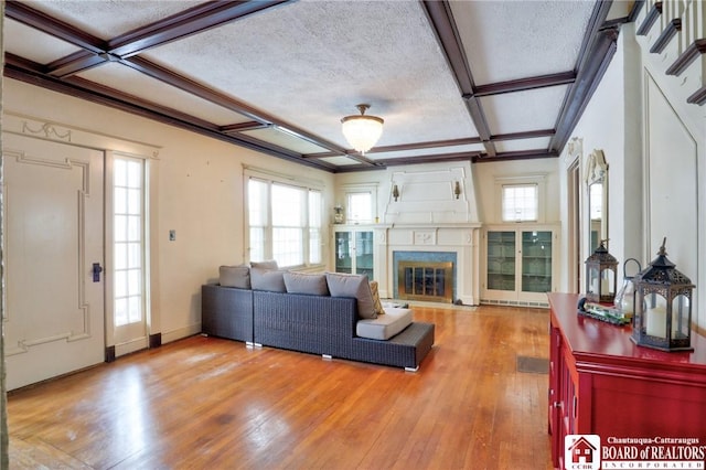 living room with a large fireplace, wood-type flooring, coffered ceiling, and a textured ceiling