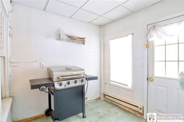 kitchen with plenty of natural light, a baseboard heating unit, and a drop ceiling