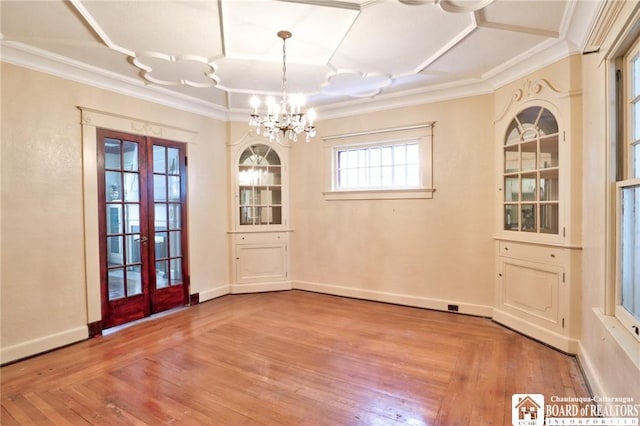 unfurnished dining area with an inviting chandelier, crown molding, light hardwood / wood-style floors, and french doors