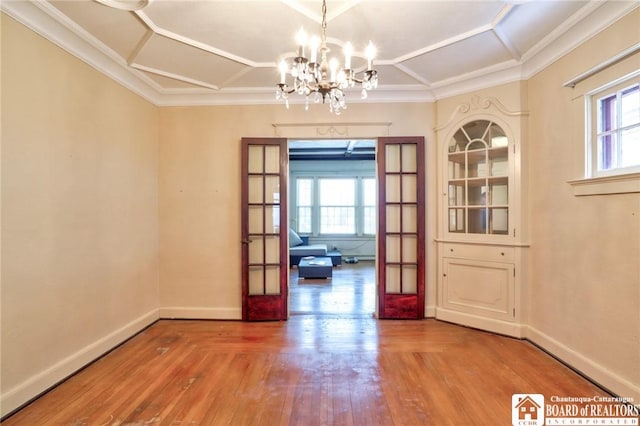 unfurnished dining area with french doors, a healthy amount of sunlight, an inviting chandelier, and wood-type flooring