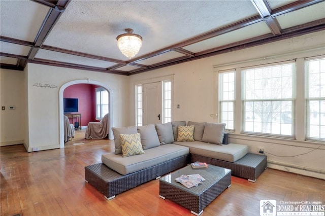 living room featuring wood-type flooring, coffered ceiling, a baseboard heating unit, and a wealth of natural light