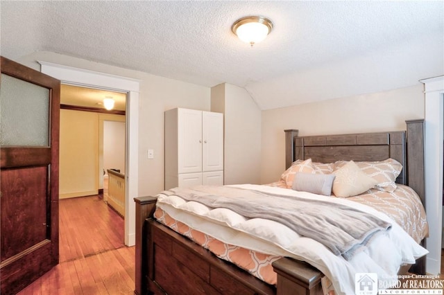 bedroom with wood-type flooring, lofted ceiling, and a textured ceiling