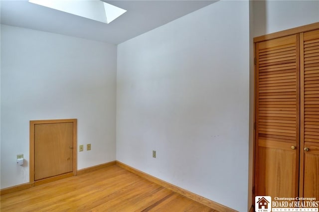 empty room with light hardwood / wood-style flooring and a skylight