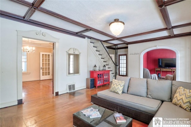 living room featuring wood-type flooring, coffered ceiling, and a wealth of natural light