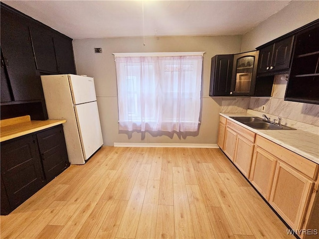 kitchen featuring white fridge, sink, light brown cabinetry, and light wood-type flooring