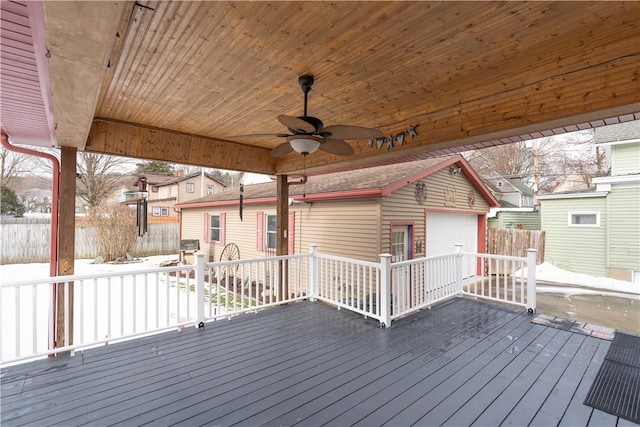 snow covered deck with a garage and ceiling fan