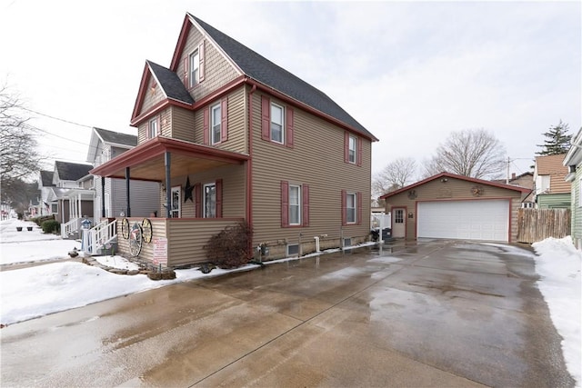 snow covered property with an outbuilding, a garage, and a porch