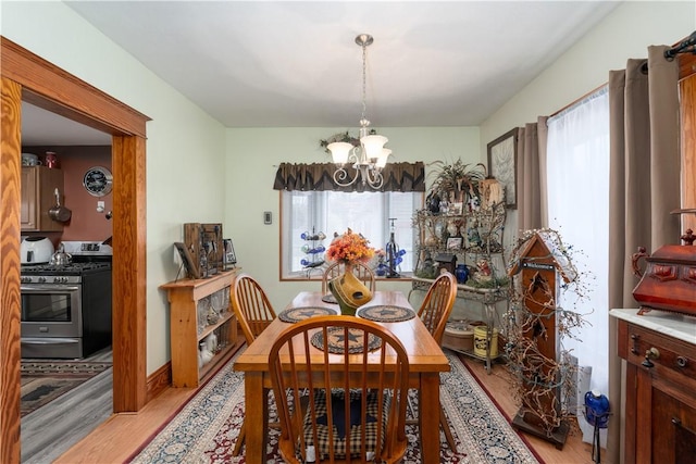 dining space with a healthy amount of sunlight, a chandelier, and light hardwood / wood-style floors