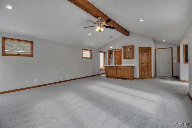 unfurnished living room featuring ceiling fan, light colored carpet, lofted ceiling with beams, and a wealth of natural light