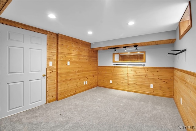 carpeted empty room with track lighting and wooden walls