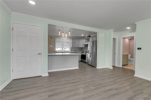 kitchen with appliances with stainless steel finishes, pendant lighting, backsplash, and light wood-type flooring