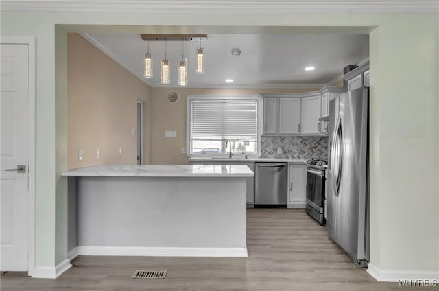 kitchen featuring hanging light fixtures, ornamental molding, appliances with stainless steel finishes, and kitchen peninsula