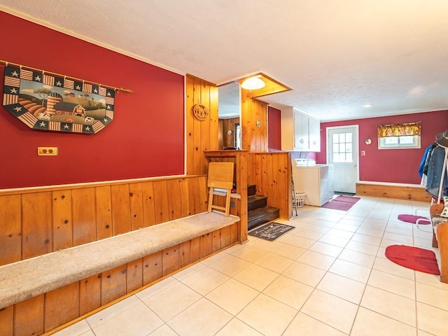 interior space with tile patterned flooring, washer / dryer, and wood walls