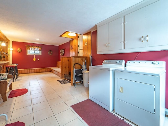 washroom featuring cabinets, light tile patterned flooring, and washer and clothes dryer