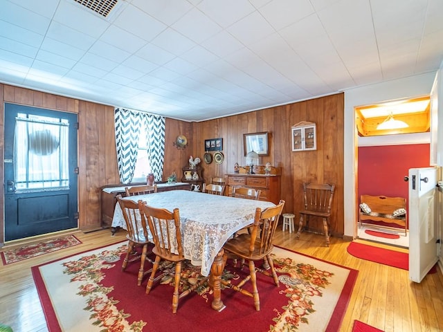 dining area featuring light hardwood / wood-style floors and wood walls