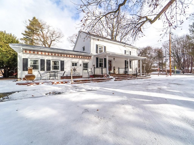 snow covered house featuring a porch